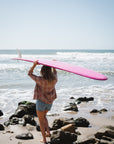 woman holding surfboard wearing summer softy flannel in orange/blue with denim shorts at the beach