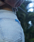 detail shot of denim surf shorts back pocket with 'ARIKO' logo on blue tab