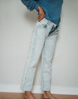 woman pulling on surf jeans with teal post surf crew sweatshirt