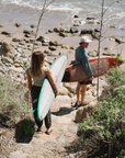 two surfers in ARIKO clothing walking down to the beach