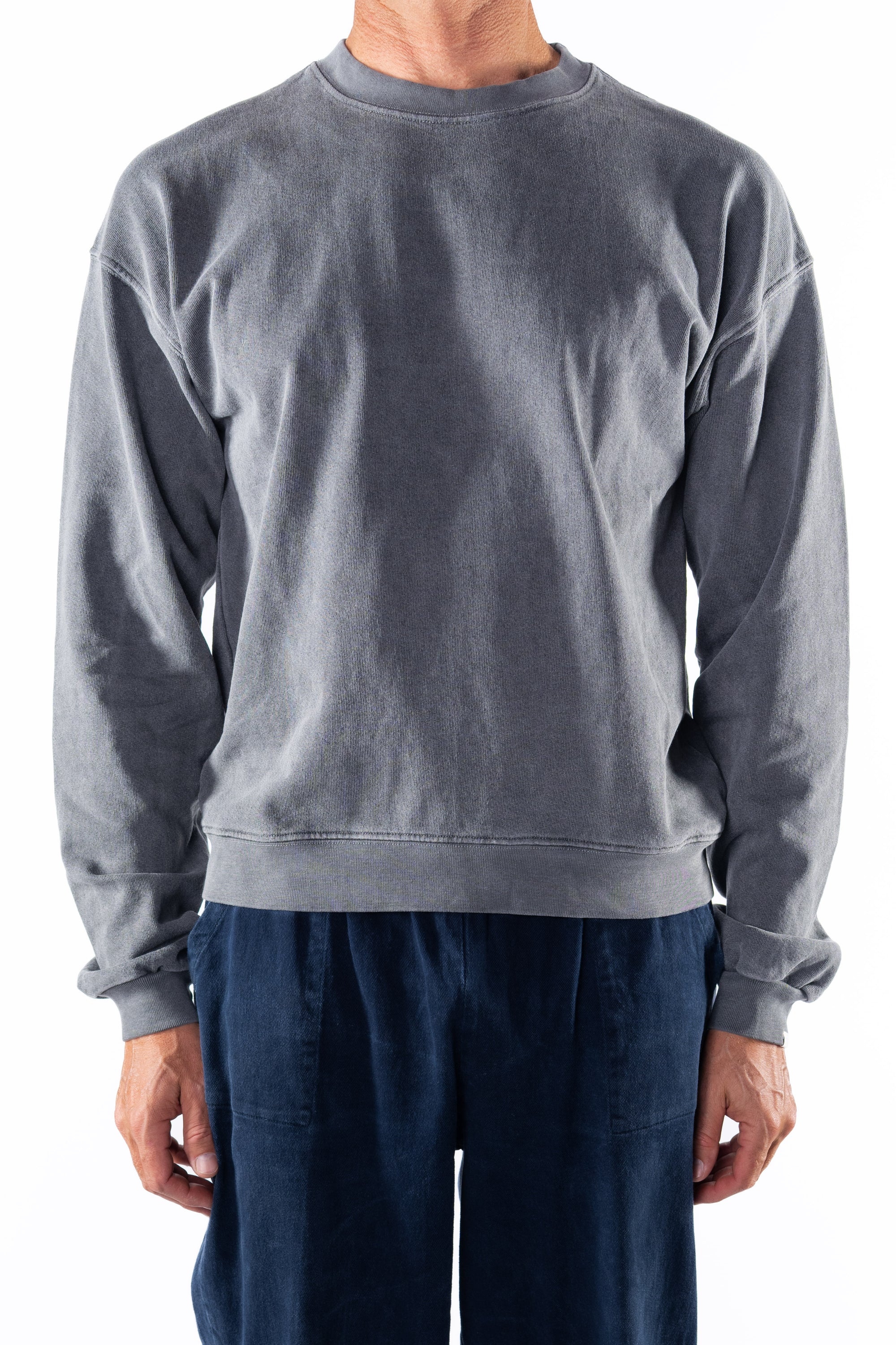 Person wearing a gray sweatshirt and navy day pants on a white background