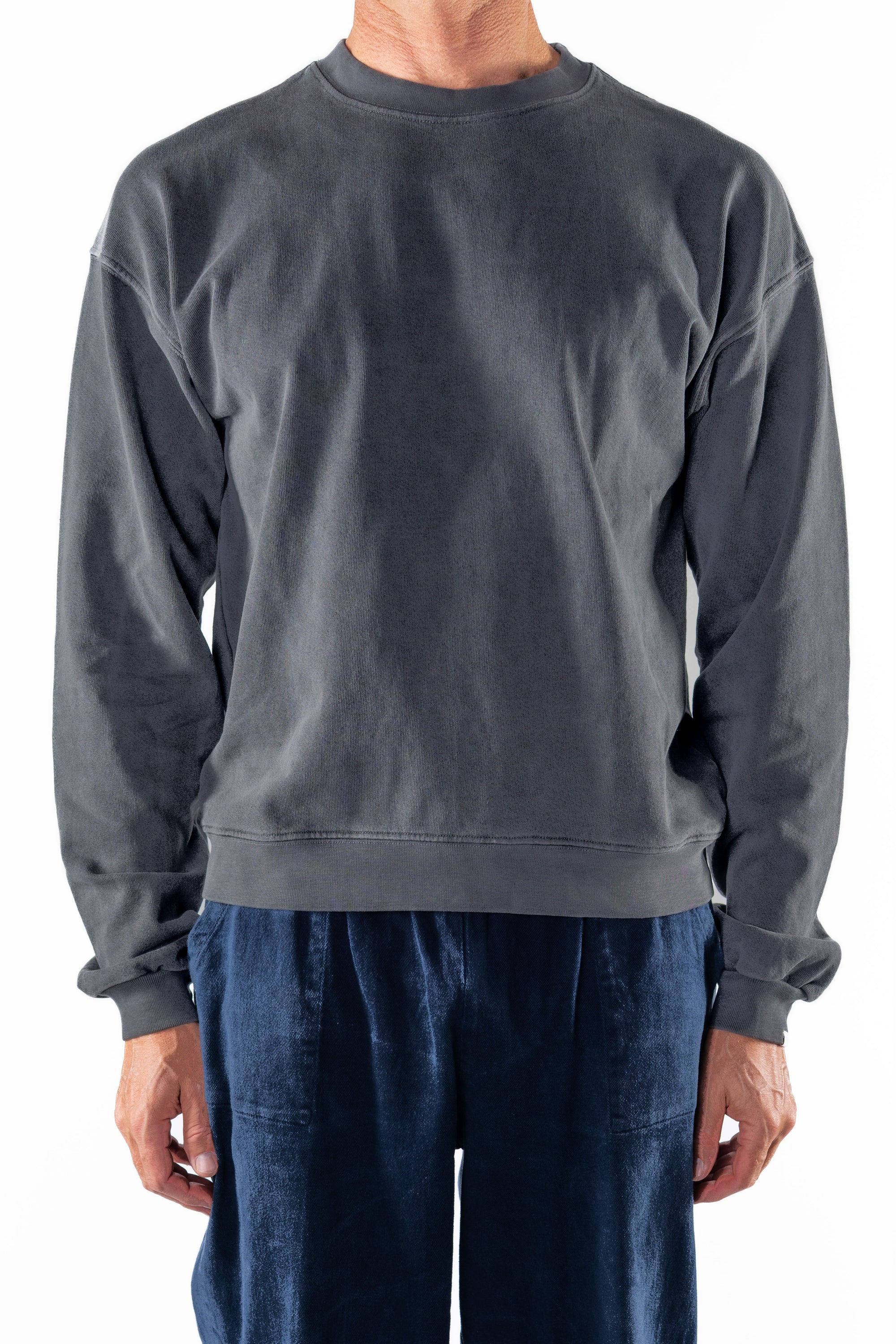 Person wearing a dark gray sweatshirt and navy day pants on a white background