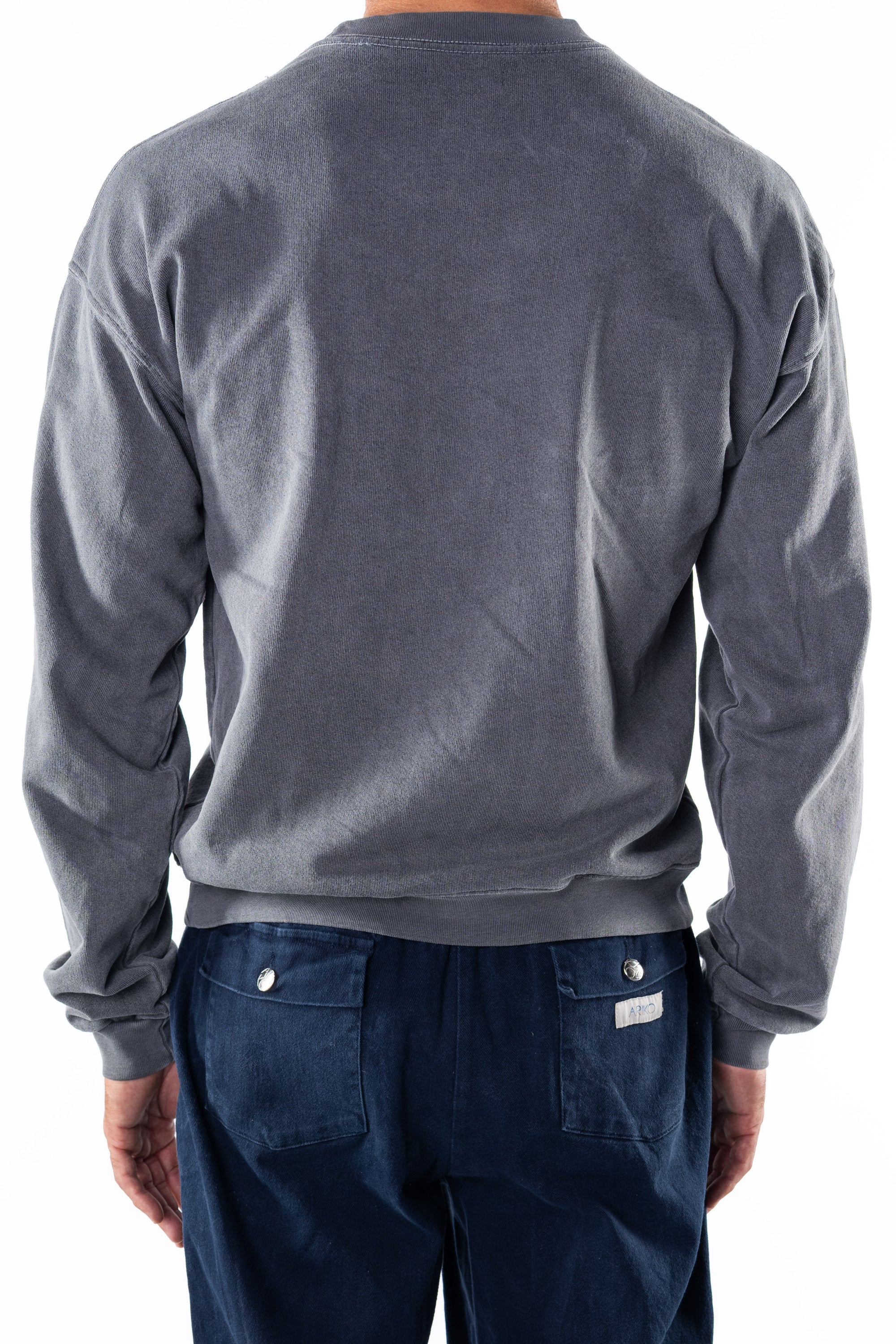 Back view of a person wearing a gray sweatshirt and navy day pants on a white background
