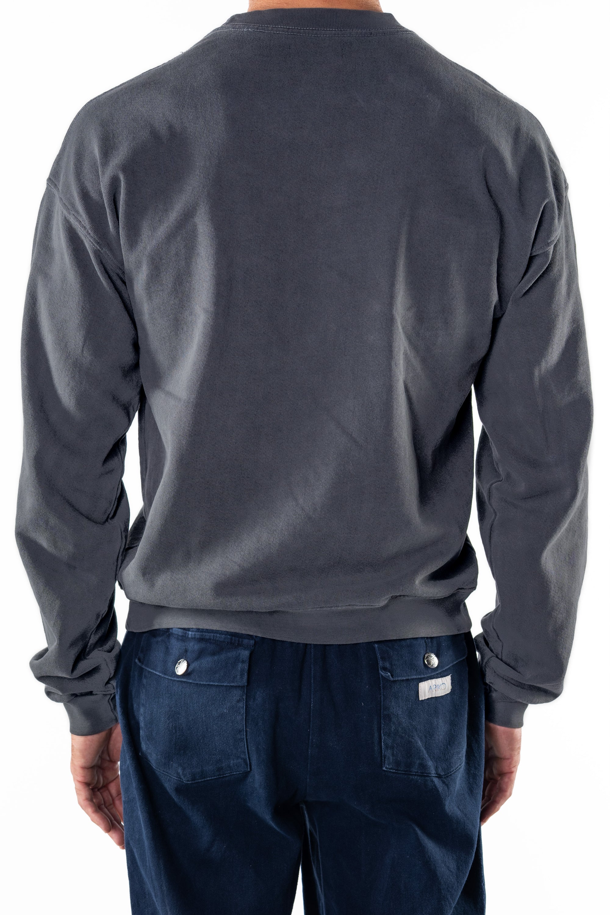 Back view of a person wearing a dark gray sweatshirt and navy day pants on a white background