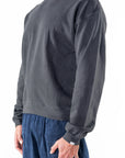 Side front view of a person wearing a dark gray sweatshirt and navy day pants on a white background