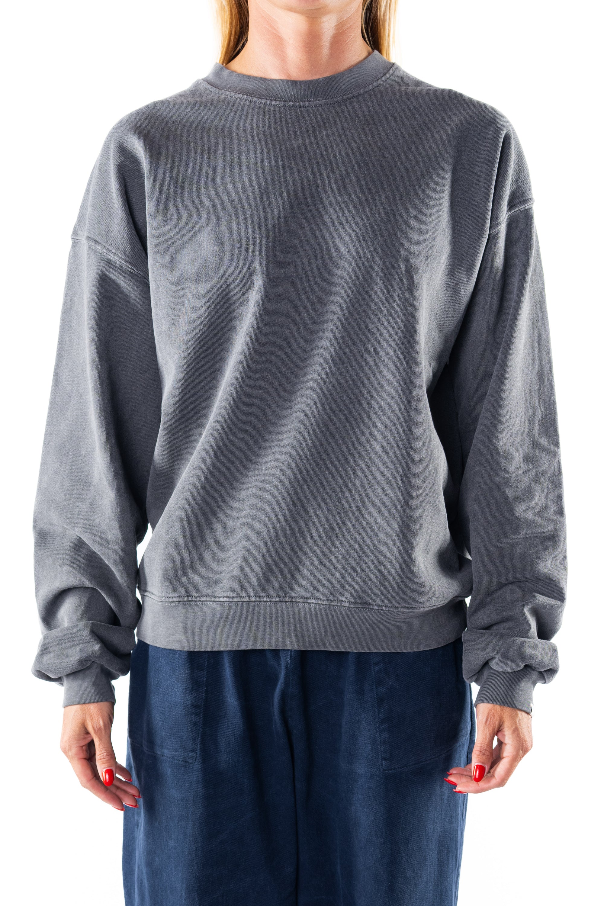 Woman wearing a gray sweatshirt and navy day pants on a white background