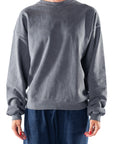 Woman wearing a gray sweatshirt and navy day pants on a white background