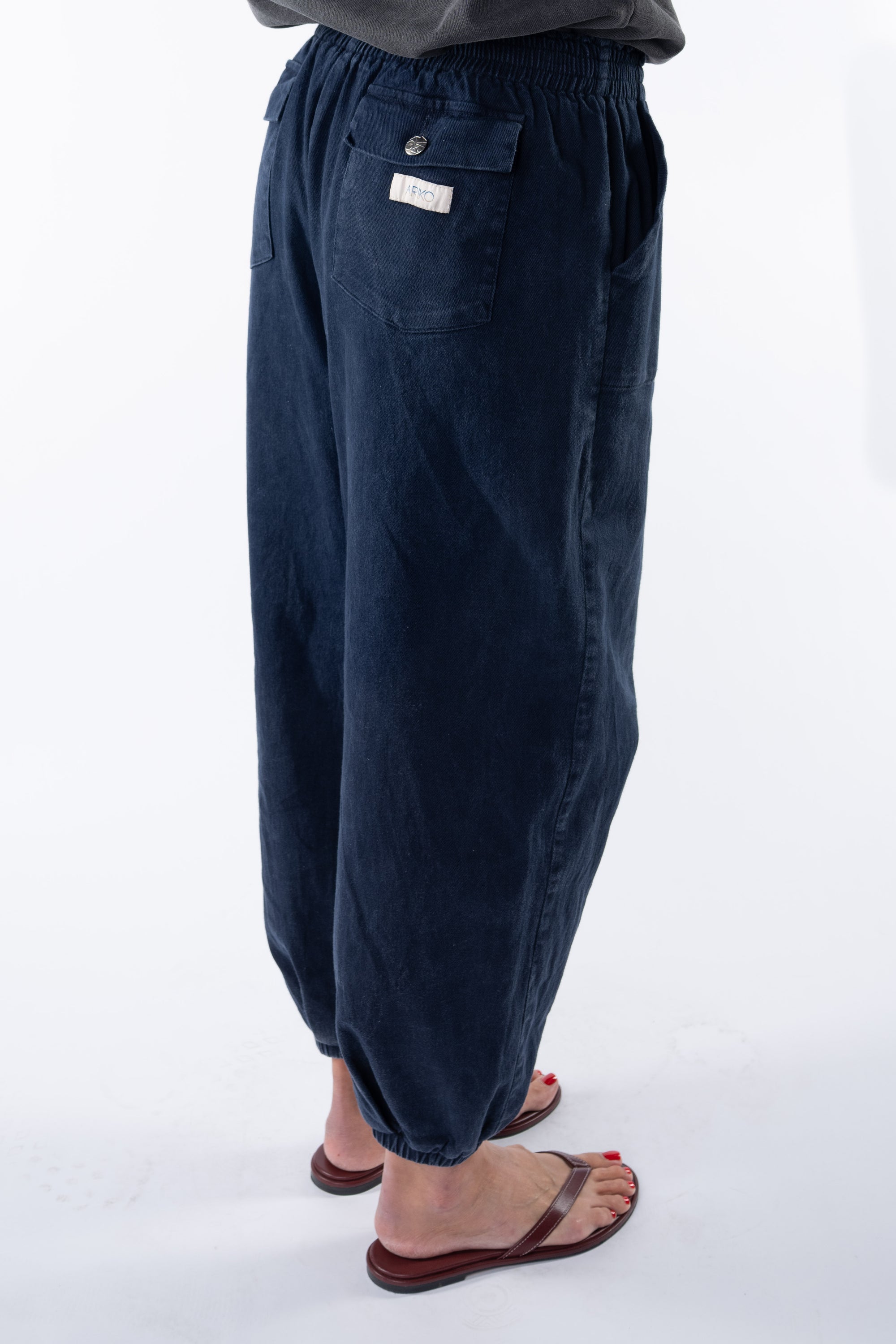 Side view of a woman wearing navy day pants on a white background