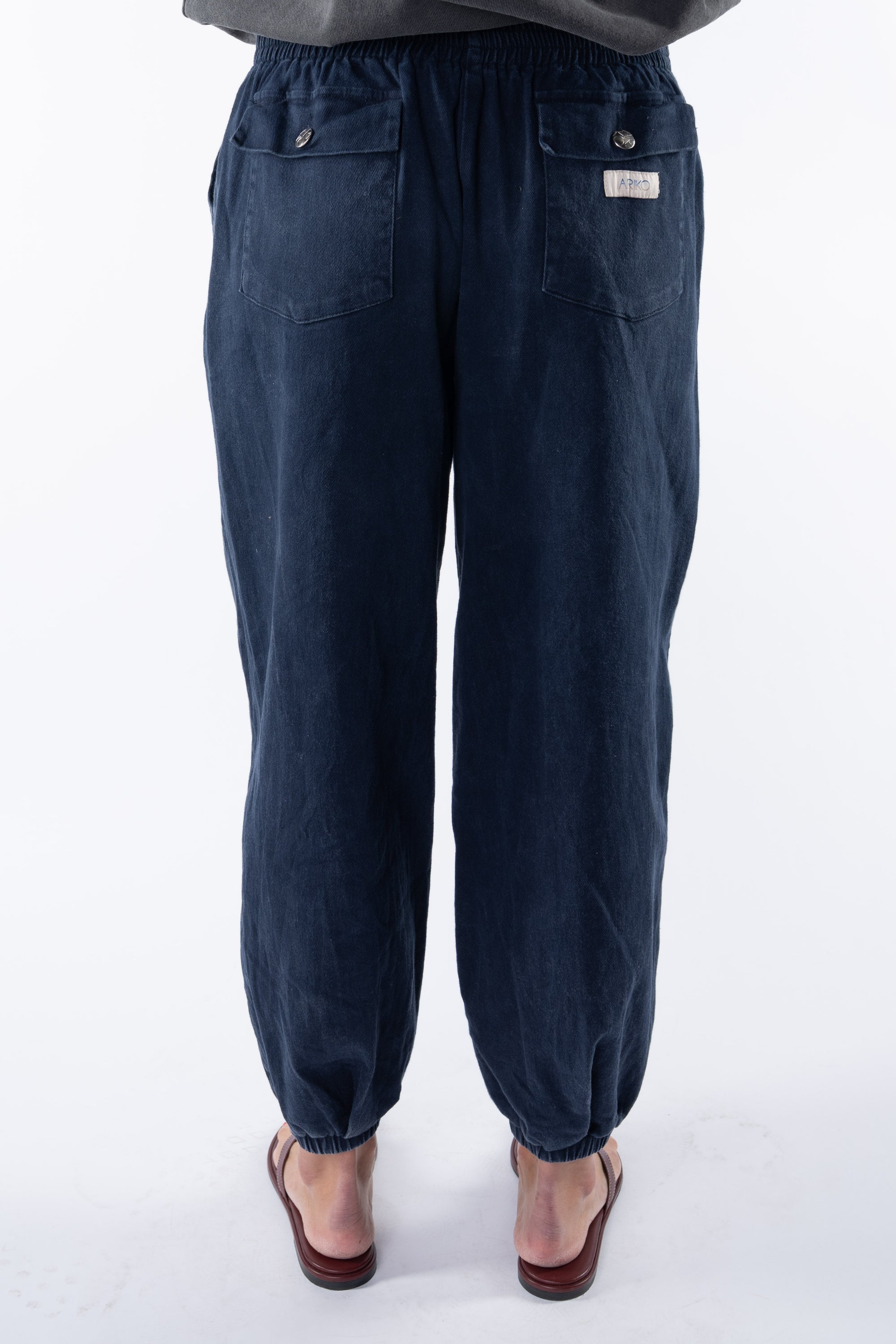 Back view of a woman wearing navy day pants on a white background