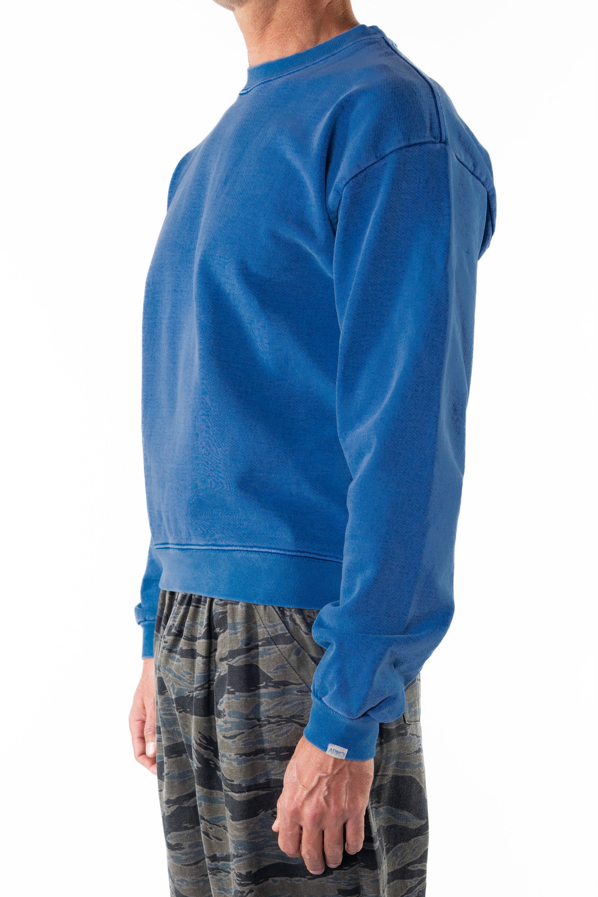 Side front view of a person wearing a blue wave sweatshirt on a white background