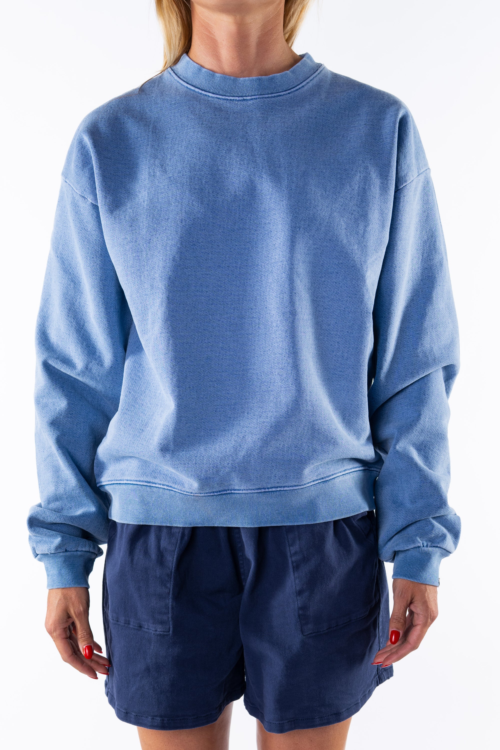 Woman wearing a blue sweatshirt and navy day shorts on a white background
