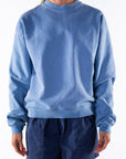 Woman wearing a blue sweatshirt and navy day shorts on a white background