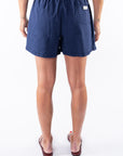 Back view of a woman wearing navy blue day shorts on a white background