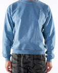 Person wearing a teal sweatshirt and ocean tiger camo day shorts on a white background