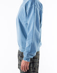 Side view of a person wearing a teal sweatshirt and ocean tiger camo day shorts on a white background