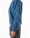 Person wearing a teal sweatshirt and ocean tiger camo shorts on a white background