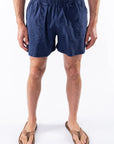 Person wearing navy blue day shorts on a white background