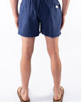 Back view of a person wearing navy blue day shorts on a white background
