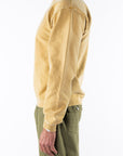 Side view of a person wearing a sunrise yellow sweatshirt and army green day pants on a white background