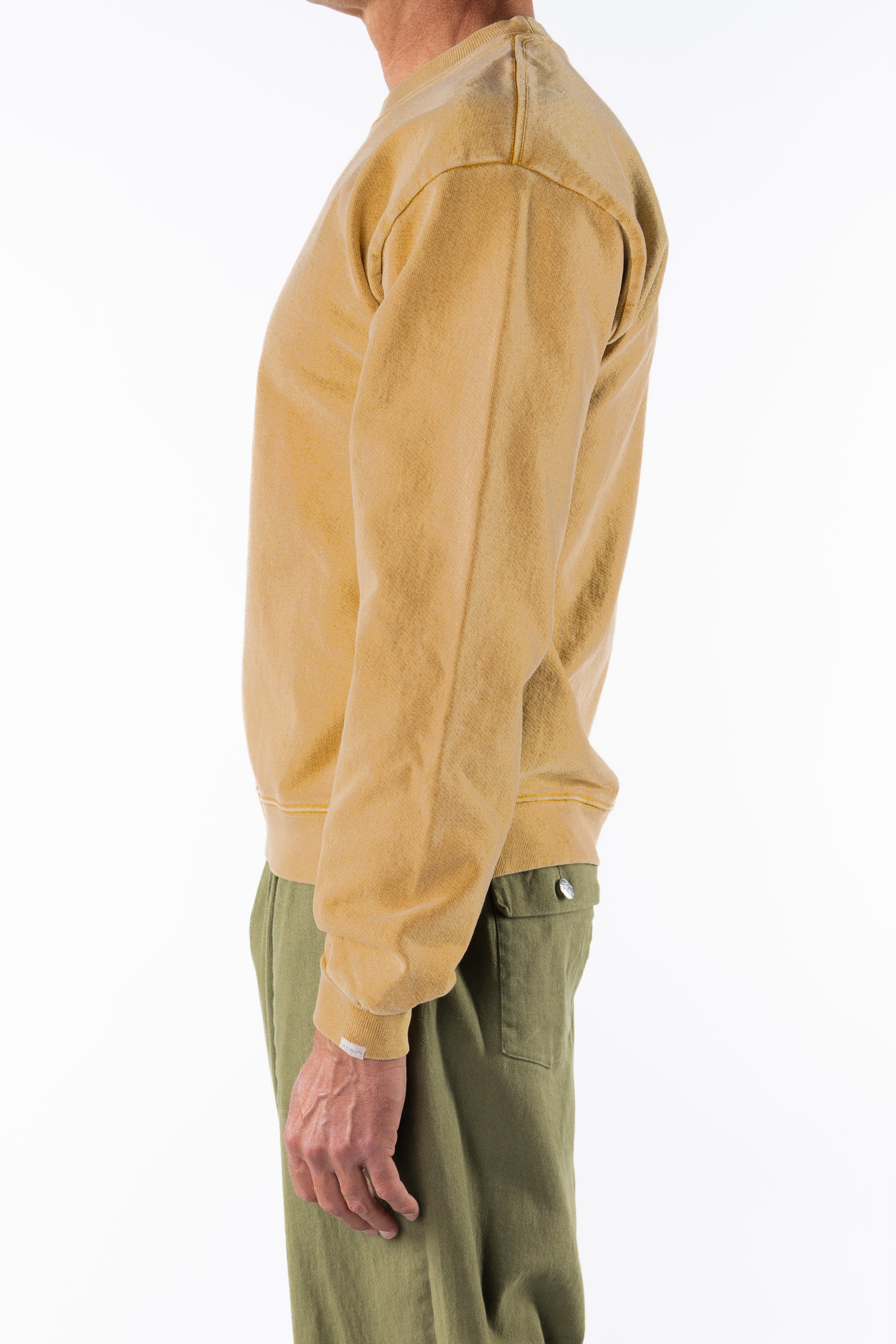 Side view of a person wearing a sunrise yellow sweatshirt and army green day pants on a white background