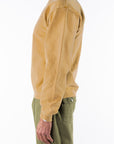 Side view of a person wearing a sunrise yellow sweatshirt and army green day pants on a white background