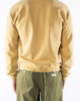 Back view of a person wearing a sunrise yellow sweatshirt and army green day pants on a white background
