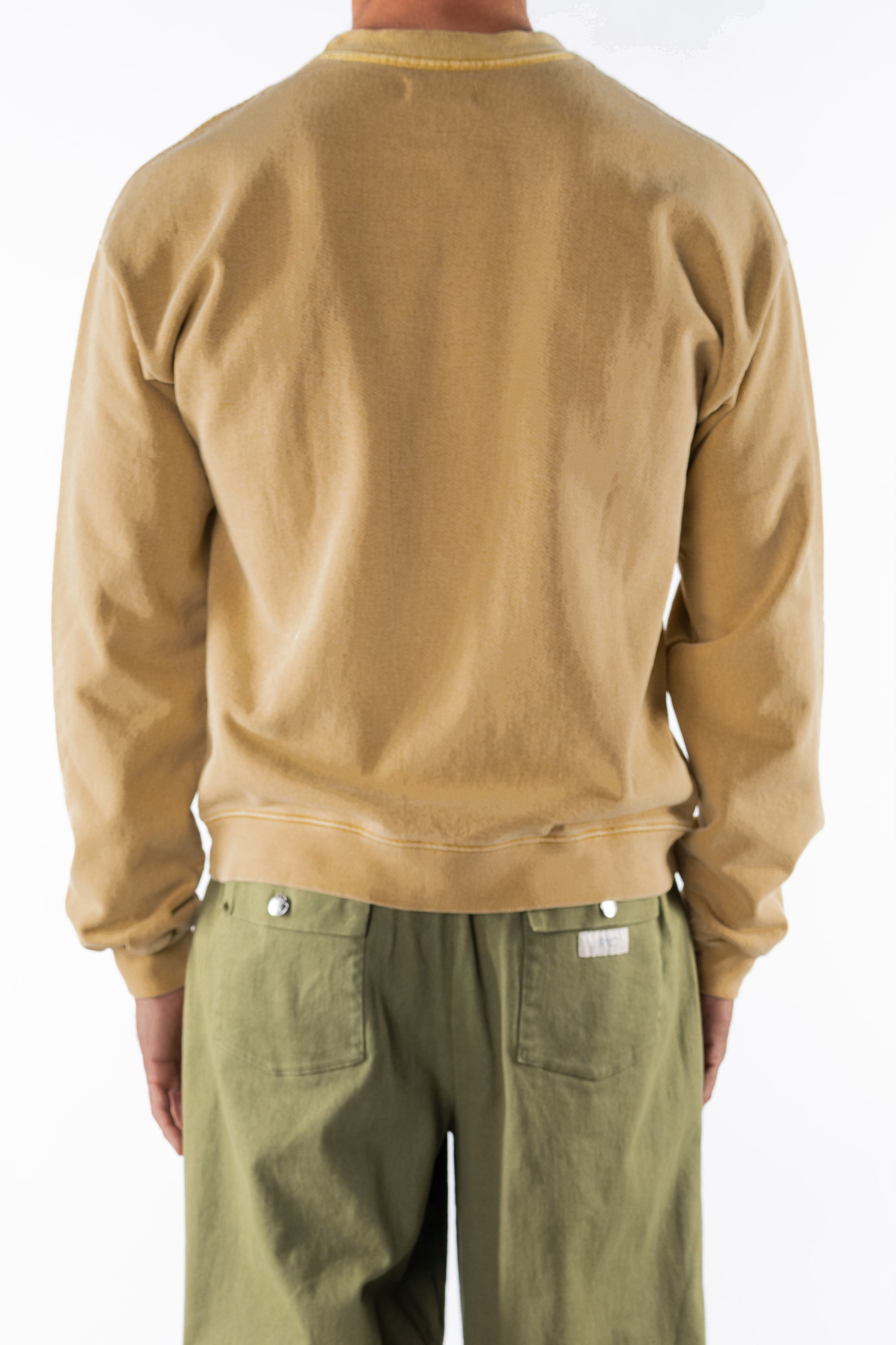Back view of a person wearing a sunrise yellow sweatshirt and army green day pants on a white background
