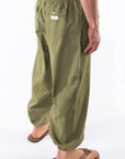 Side back view of army green day pants worn by a person on a white background