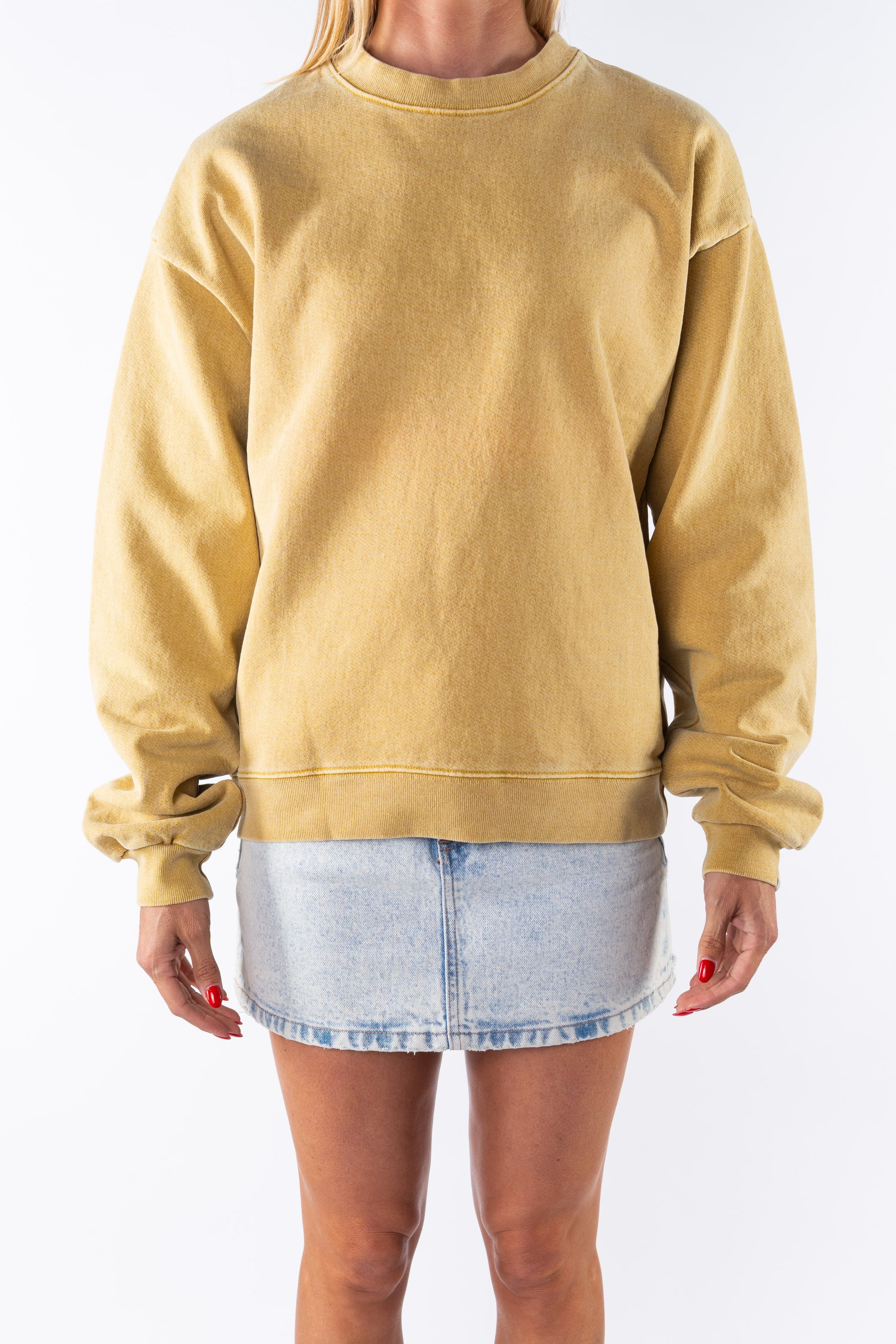 Woman wearing a sunrise yellow sweatshirt and denim mini skirt on a white background