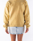 Woman wearing a sunrise yellow sweatshirt and denim mini skirt on a white background