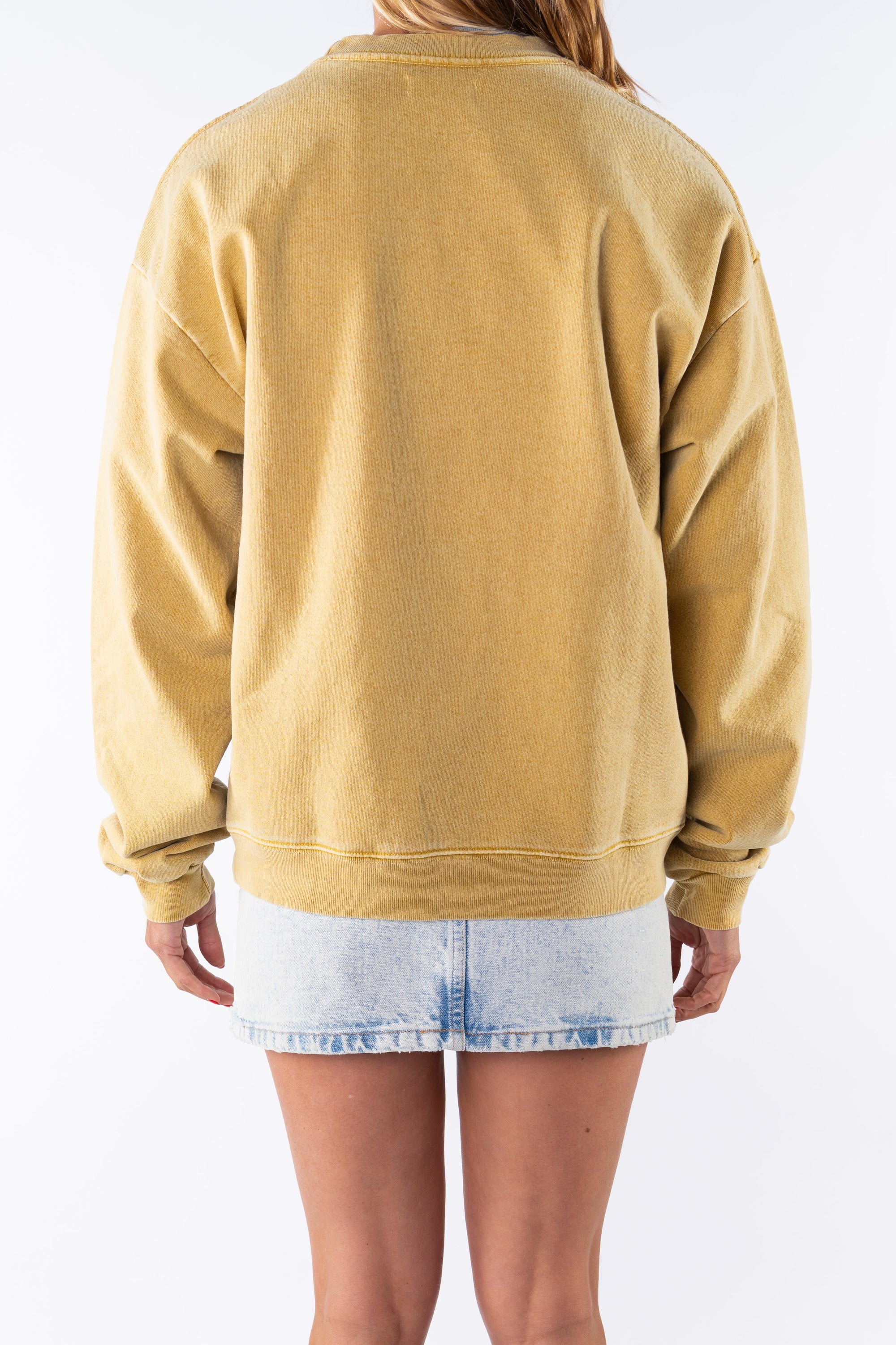 Back view of a woman wearing a sunrise yellow sweatshirt and denim mini skirt on a white background