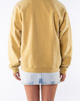 Back view of a woman wearing a sunrise yellow sweatshirt and denim mini skirt on a white background