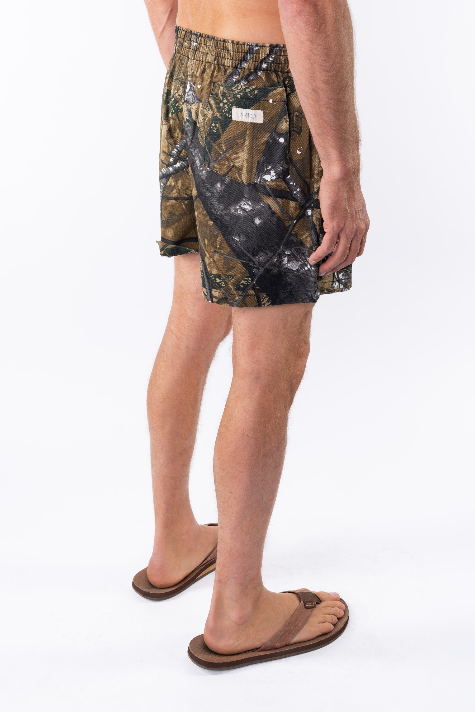 Side back view of a person wearing real tree camo day shorts on a white background.
