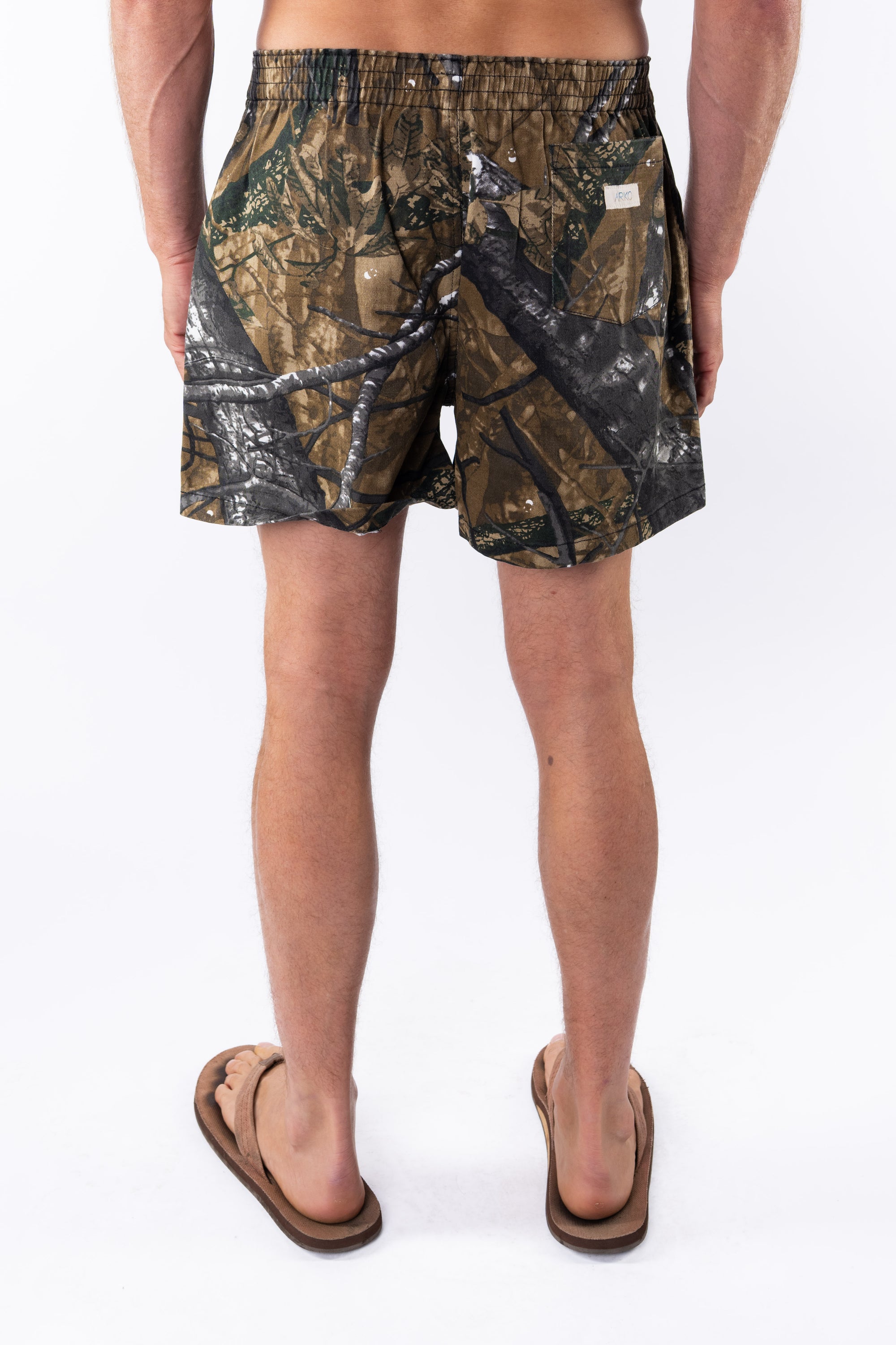Back view of a person wearing real tree camouflage day shorts on a white background