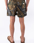 Back view of a person wearing real tree camouflage day shorts on a white background