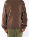 Woman wearing a brown sweatshirt and army green day pants on a white background