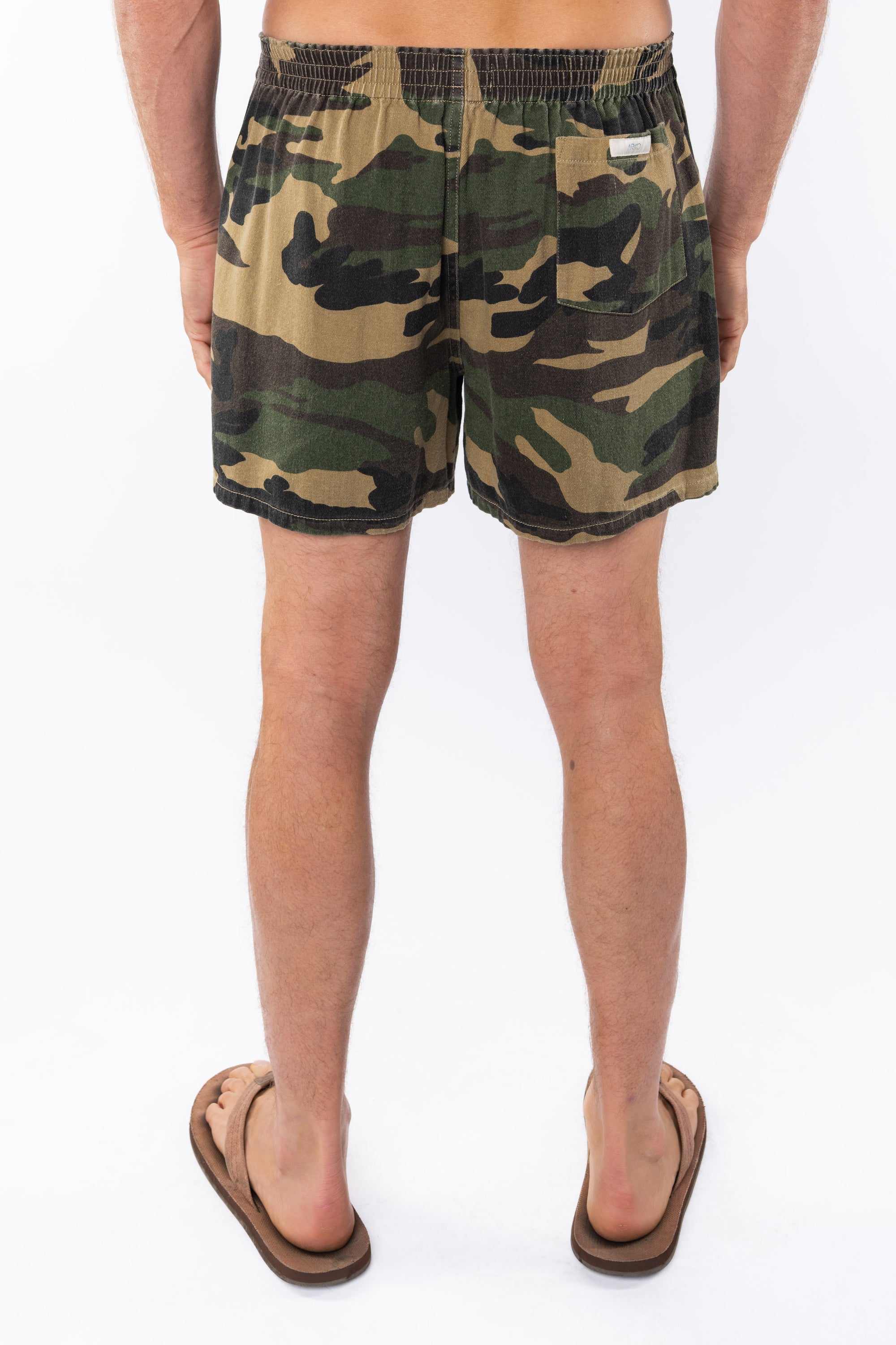 Back view of camouflage day shorts worn by a person on a white background