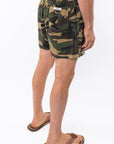 Side back view of a person wearing camouflage day shorts on a white background