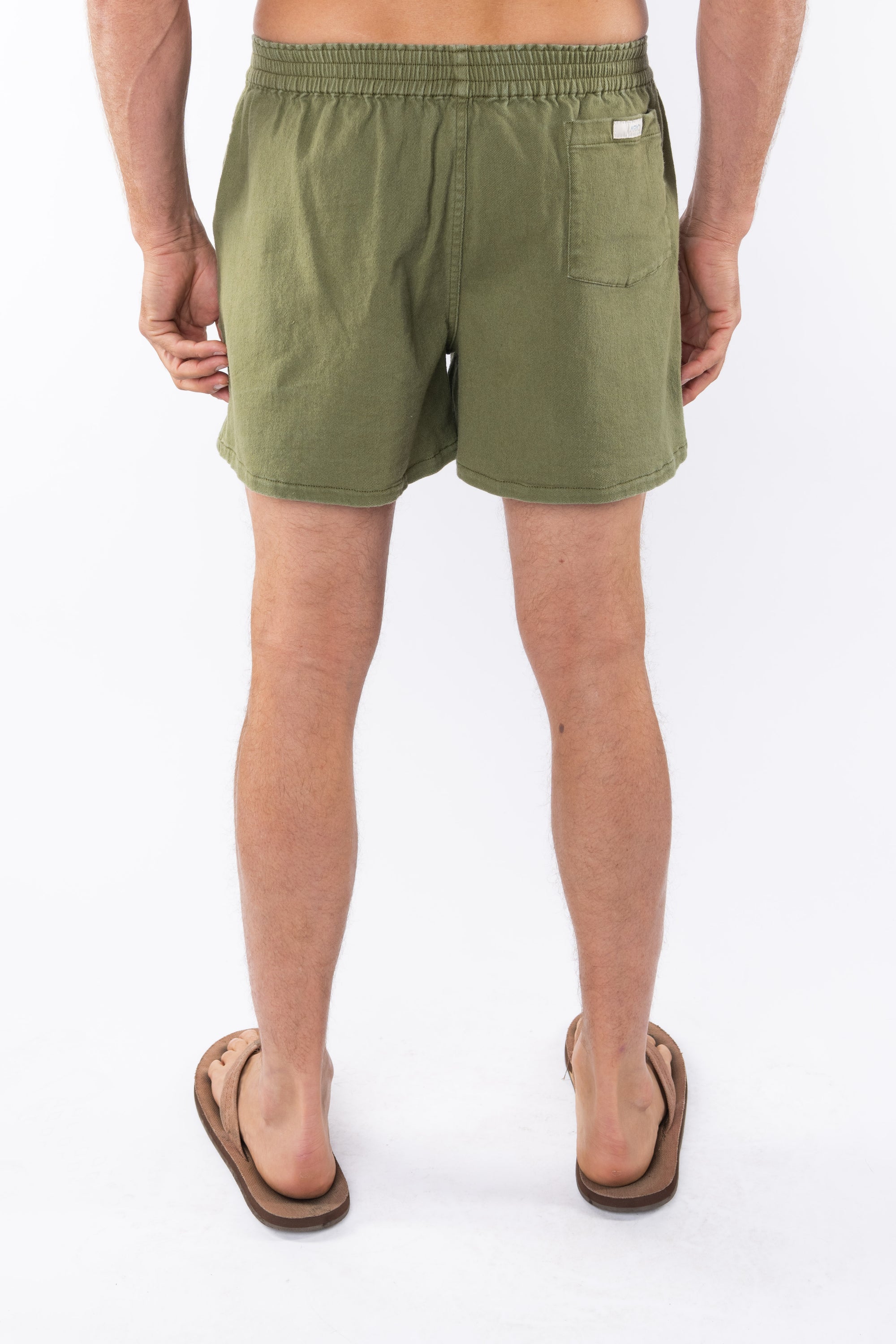 Back view of army green day pants worn by a person on a white background
