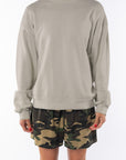 Woman wearing a beige sweatshirt and camouflage day shorts on a white background