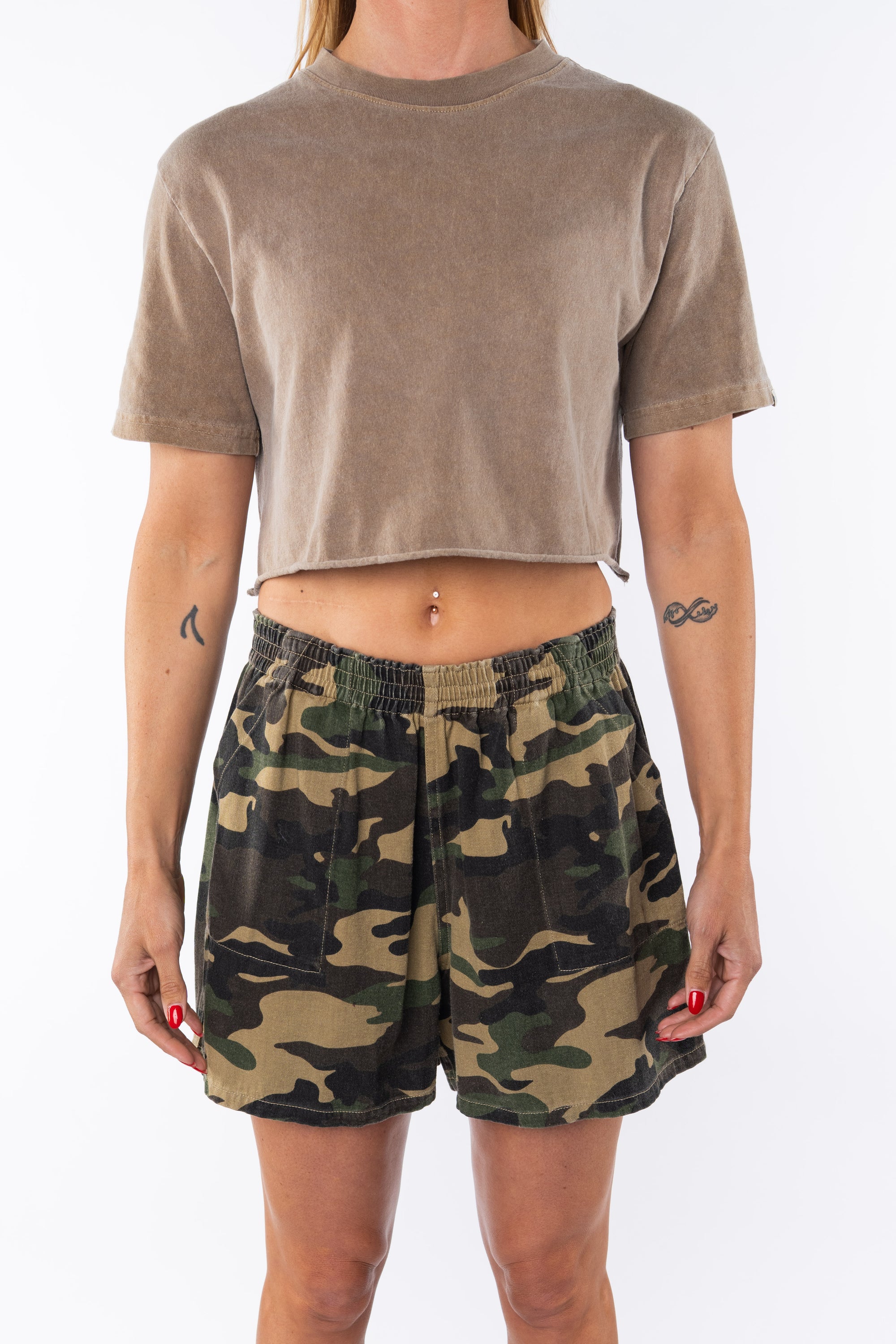 Woman wearing a brown beach crop t-shirt and camouflage day shorts on a white background
