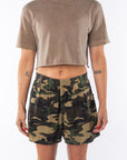 Woman wearing a brown beach crop t-shirt and camouflage day shorts on a white background