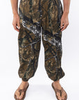 Real tree camouflage day pants worn by a person on a white background