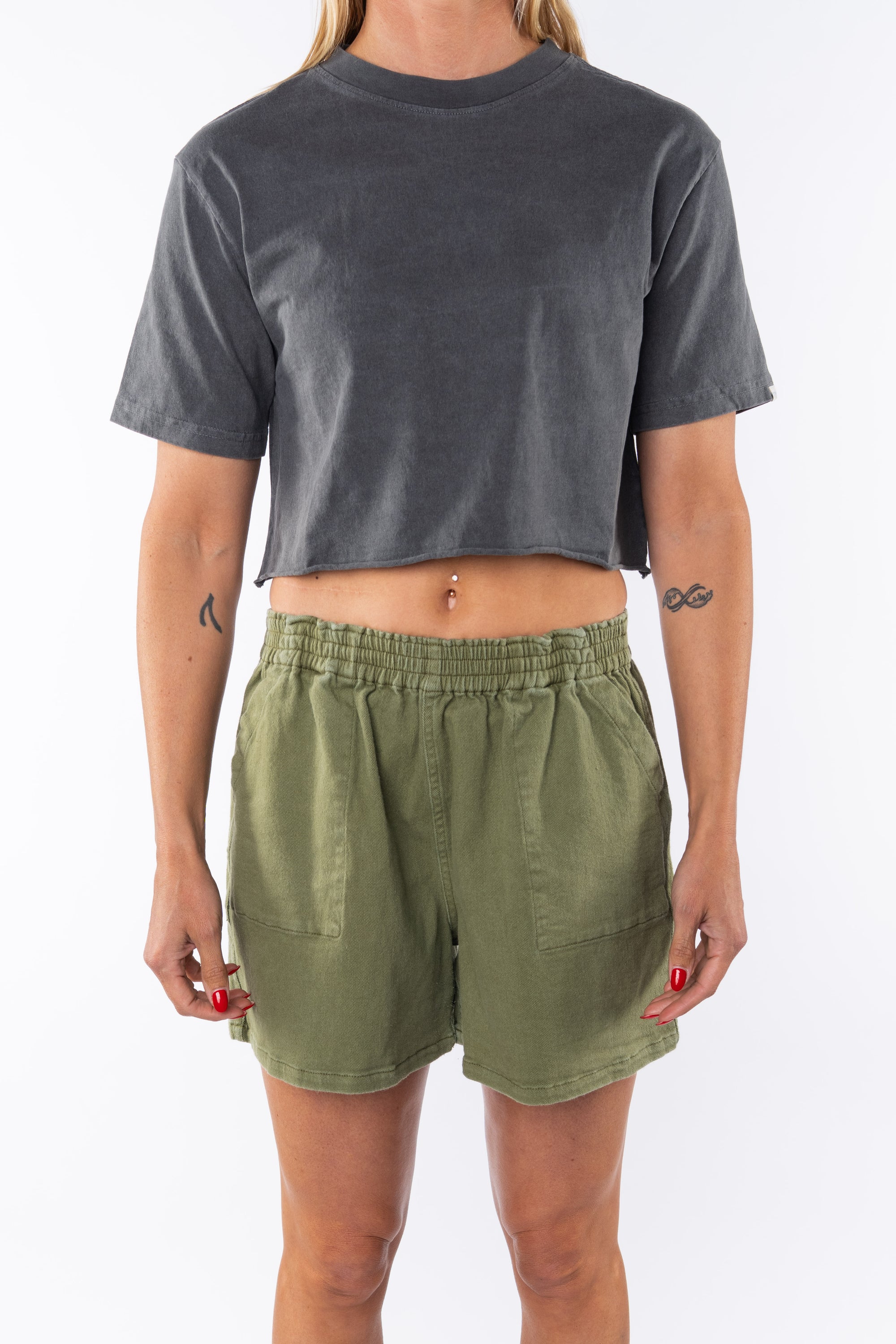 Woman wearing a gray beach crop t-shirt and army green day shorts on a white background