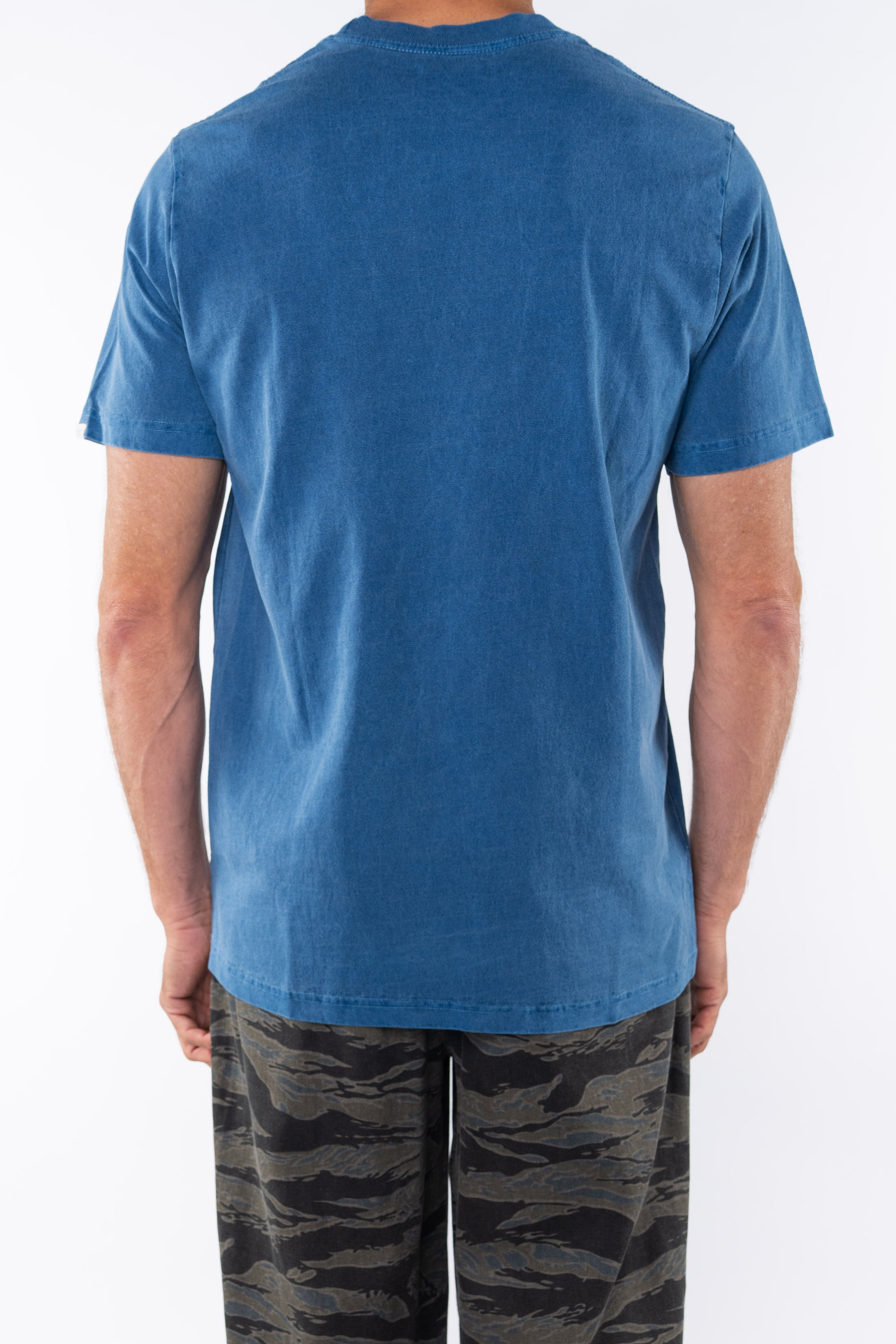 Back view of a man wearing a teal beach t-shirt with ocean tiger camo day pants on a white background 