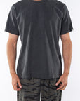 Man wearing a plain dark gray beach t-shirt and ocean tiger camo day pants on a white background