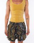 Woman wearing a Scallop Tank in Sunrise Yellow with Real Tree Camo day shorts. 