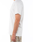 Side shot of man wearing a man wearing a Crewneck T-shirt in cream with a leopard pants on a white background.