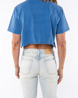 Back shot of a woman wearing Beach Crop Tee in Blue Wave with Surf Jeans. 