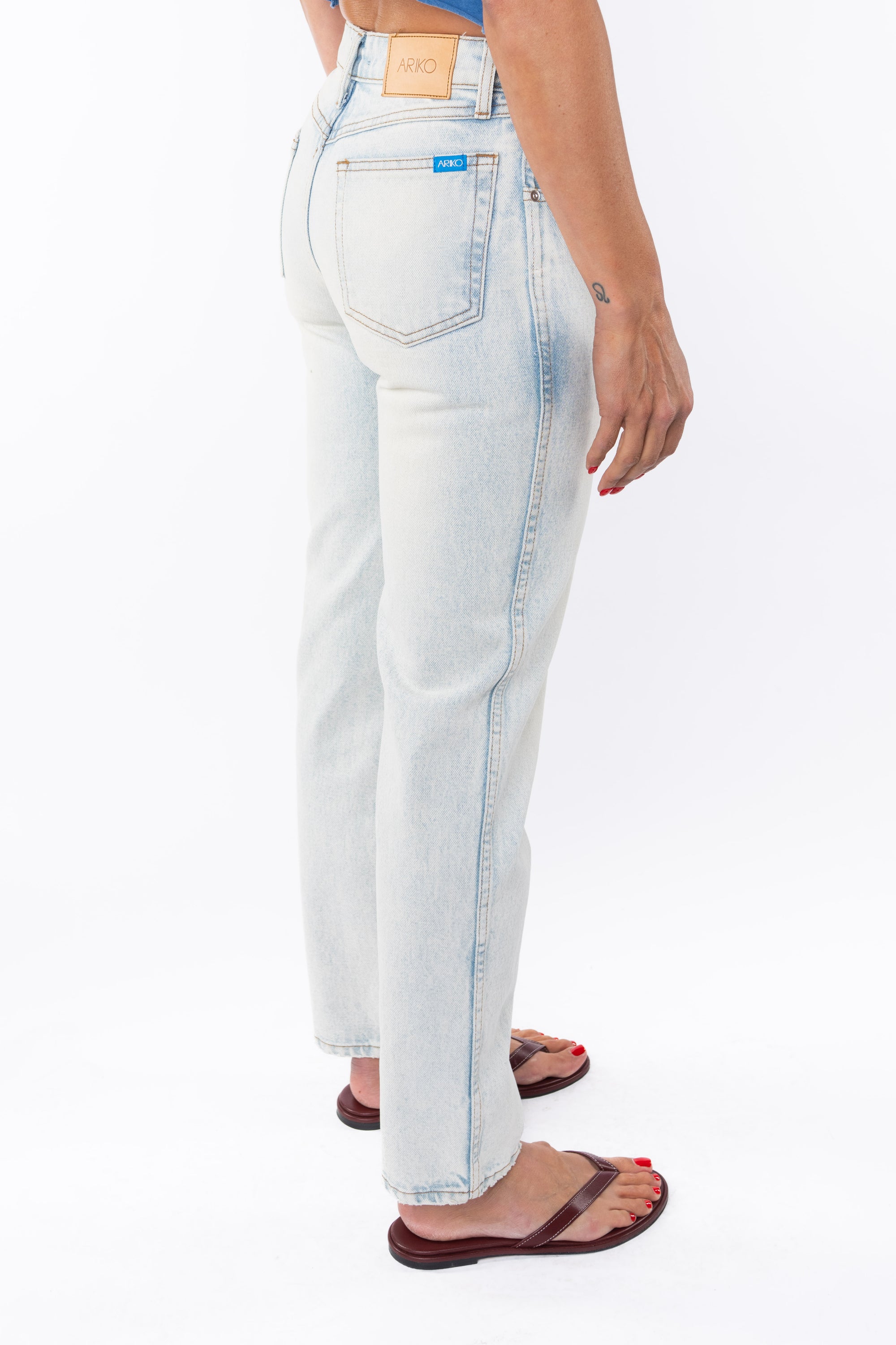 Back side view of a woman wearing light denim washed jeans on a white background